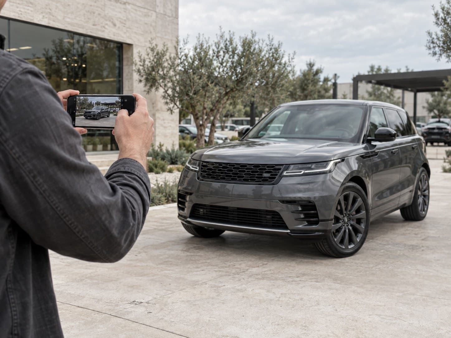 A dealership professional capturing vehicle photos on a phone
